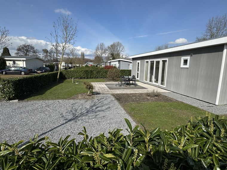 Tuin met bestraat terras en tuinset naast de recreatiewoning