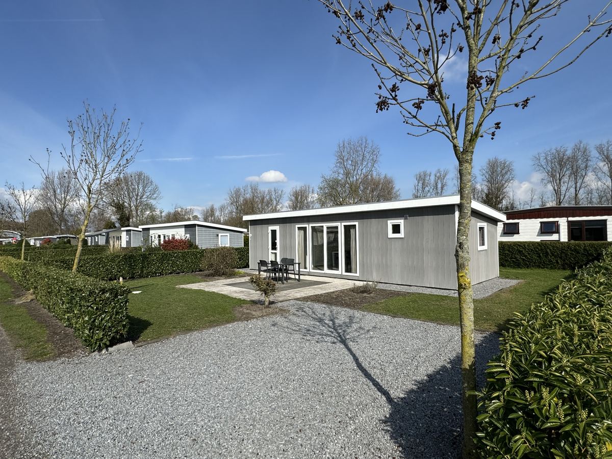 Grijs afgewerkte recreatiewoning met terras, tuinset en eigen oprit
