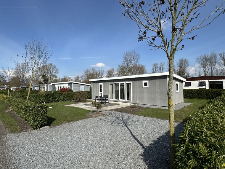 Grijs afgewerkte recreatiewoning met terras, tuinset en eigen oprit