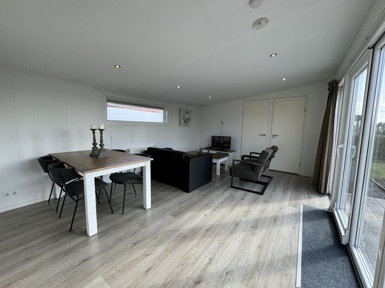 Woonkamer met eettafel, zithoek en schuifpui naar het terras