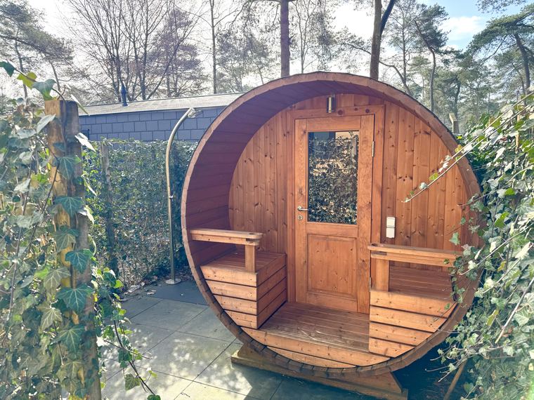 Houten barrelsauna in de omheinde tuin