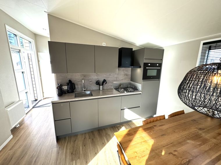 Open keuken met gaskookplaat, oven, afzuigkap en koffieapparaat