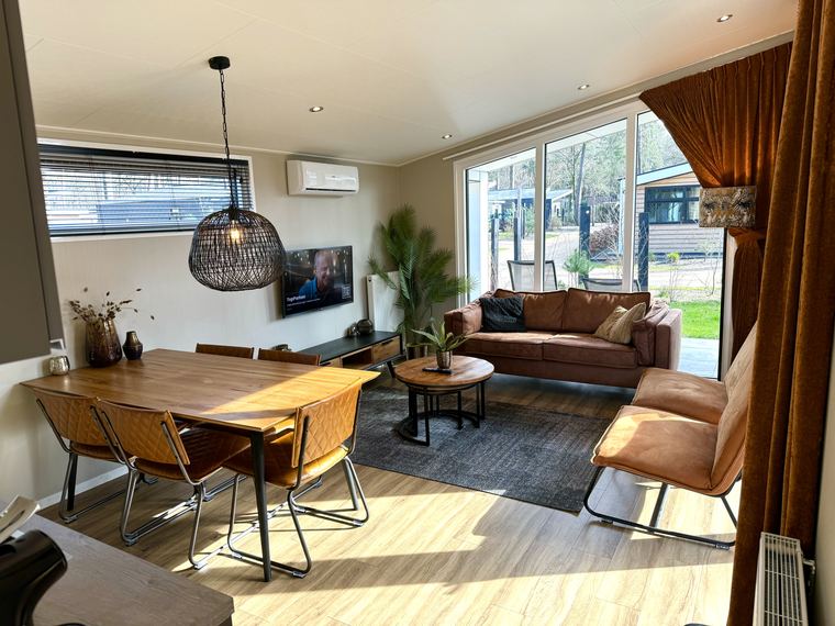 Woonkamer met eettafel, leren bank en schuifpui naar het terras